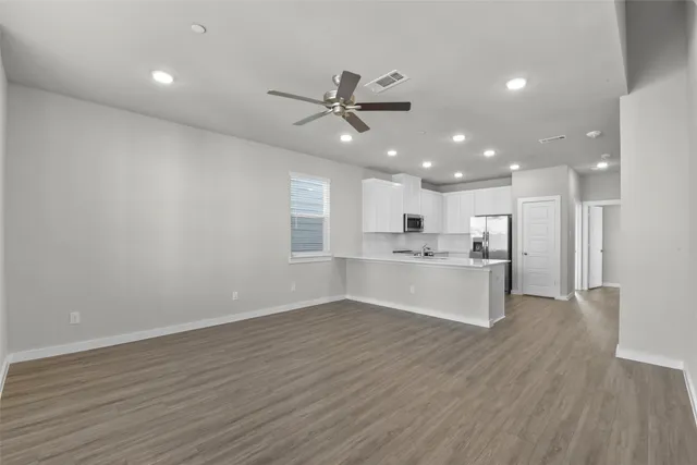 a view of kitchen with center island wooden floor stainless steel appliances and cabinets