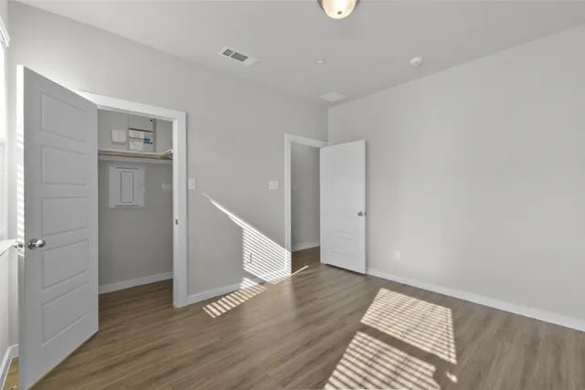 a view of an empty room with wooden floor and a window