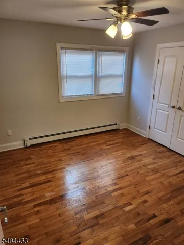 an empty room with wooden floor fan and windows