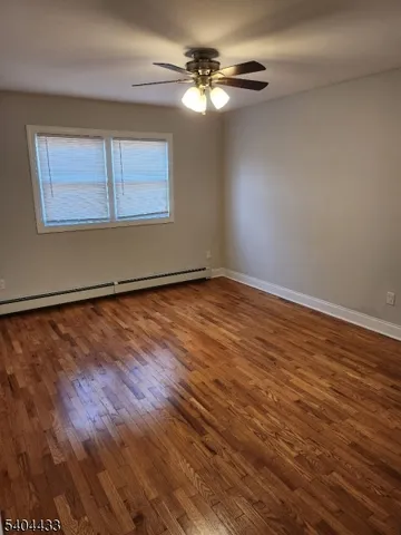 a view of an empty room with a window and wooden floor