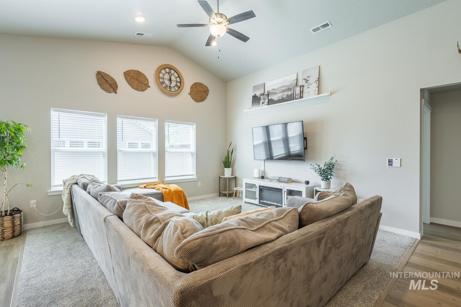 12623 Shadow Peak Street Caldwell, ID 83607 - Photo 9 of 50 Spacious living area featuring a vaulted ceiling, ceiling fan, and multiple windows with blinds