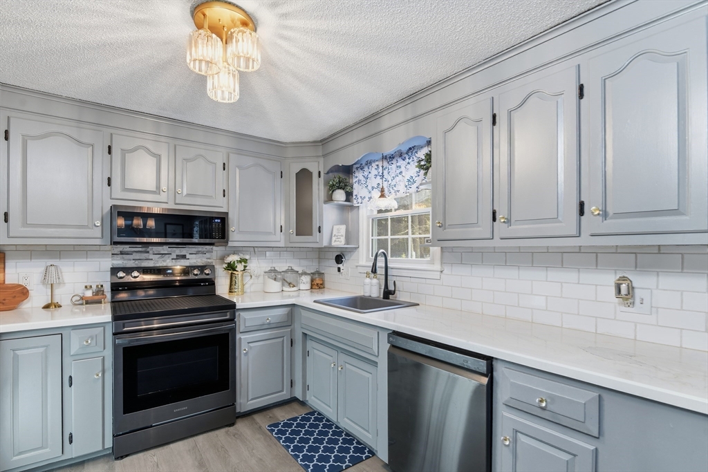 80 Walnut Street Middleboro, MA 02346 - Photo 10 of 34 a kitchen with stainless steel appliances granite countertop a sink dishwasher a stove a microwave oven with cabinets and wooden floor