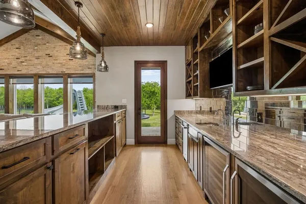 a kitchen with stainless steel appliances kitchen island granite countertop a table chairs sink and cabinets