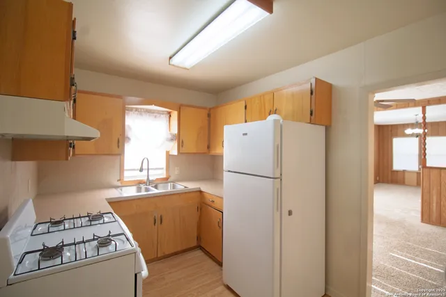 a kitchen with a refrigerator a stove top oven a sink and cabinets