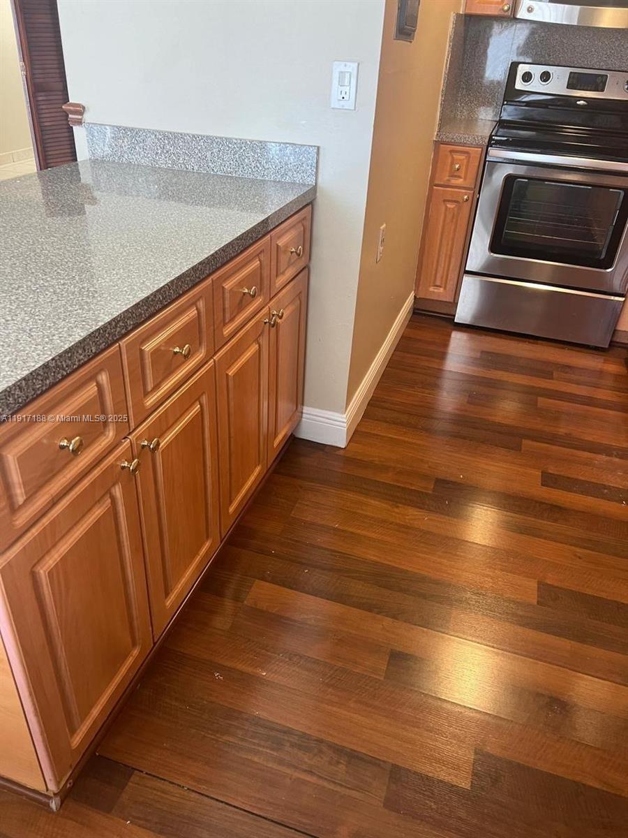5306 West 26th Avenue, Unit 102 Hialeah, FL 33016 - Photo 19 of 33 a kitchen with granite countertop wooden floors and stainless steel appliances