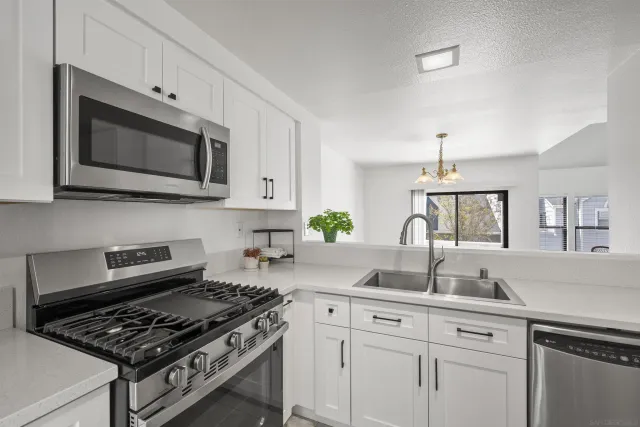 a kitchen with white cabinets a sink stove and microwave