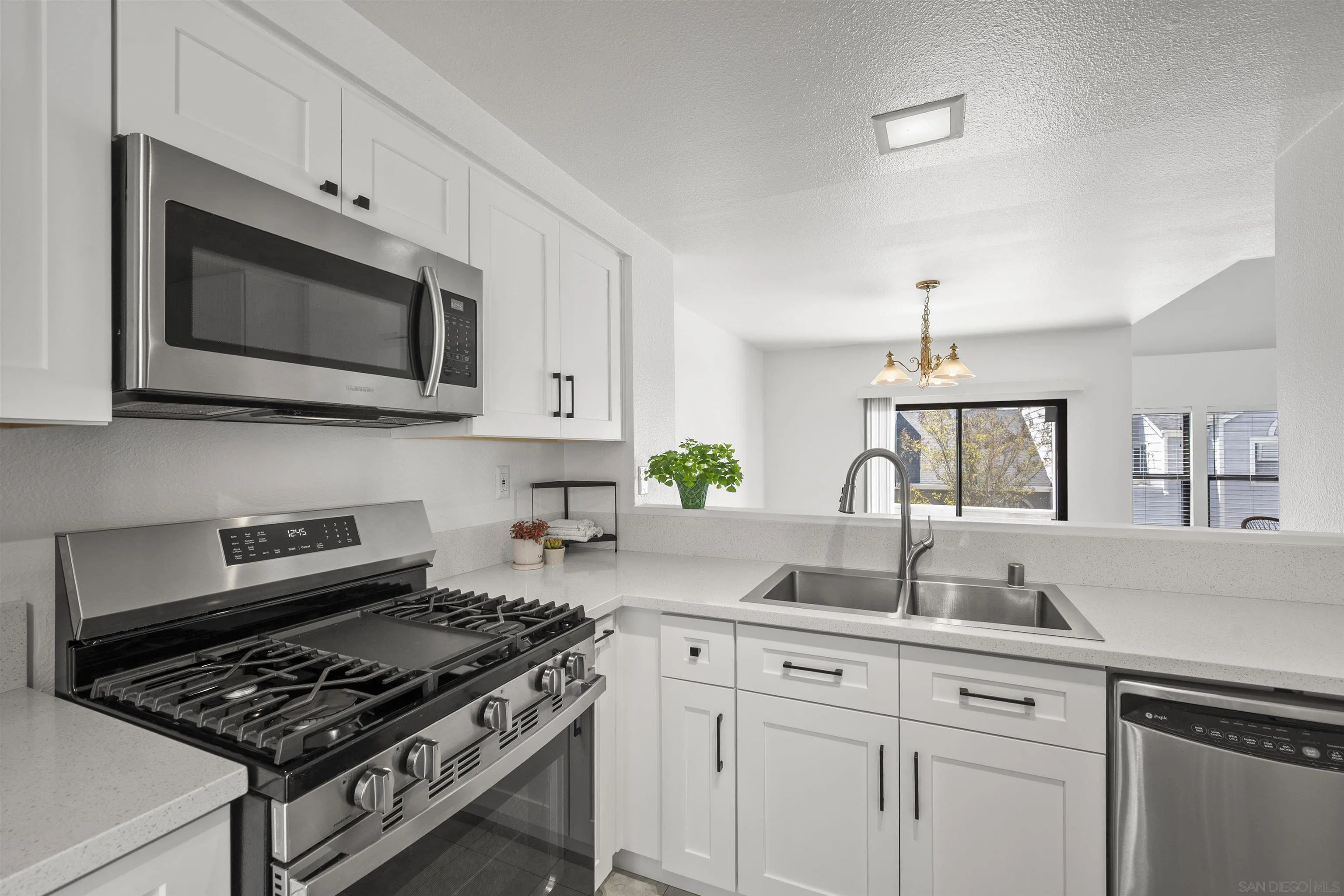 a kitchen with white cabinets a sink stove and microwave