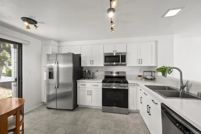 a kitchen with stainless steel appliances granite countertop a sink stove refrigerator and cabinets