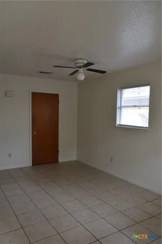 an empty room with windows and fan