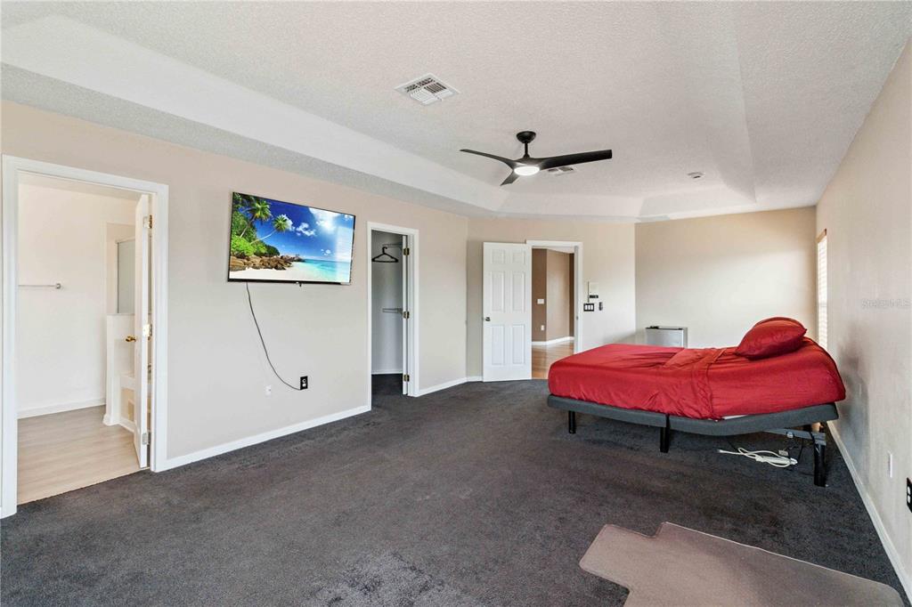 2881 Lyndscape Street Orlando, FL 32833 - Photo 13 of 30 a spacious bedroom with a bed and a chandelier