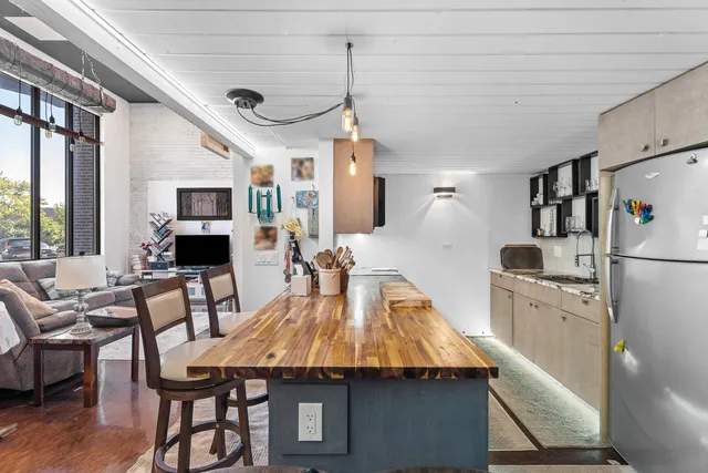 a kitchen with stainless steel appliances granite countertop a kitchen island a stove a dining table and chairs with wooden floor