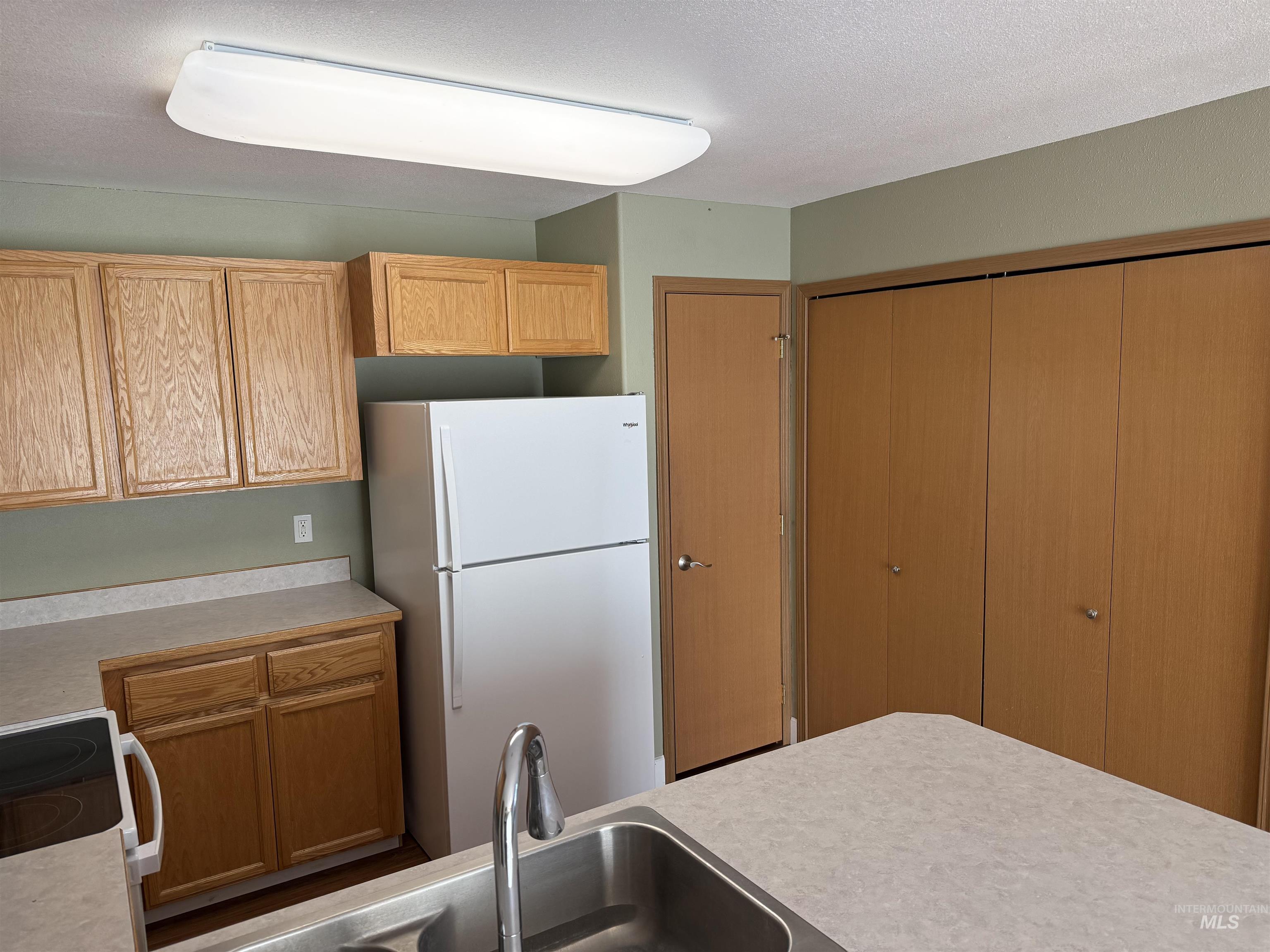 257 Pintail Lane Moscow, ID 83843 - Photo 7 of 28 Kitchen with white appliances, light countertops, wood finish cabinetry, and a textured ceiling