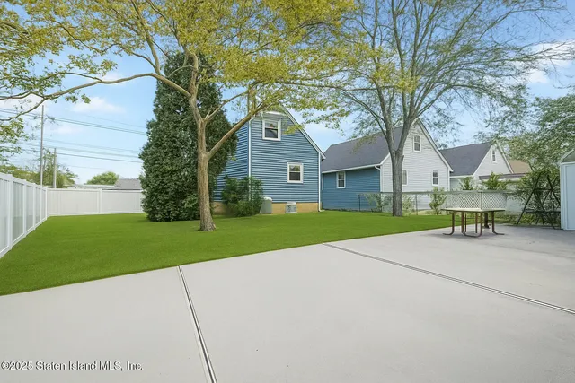 a view of a house with a yard and a large tree