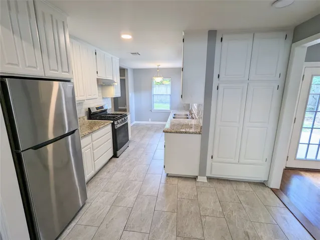 a kitchen with a refrigerator a stove top oven and cabinets