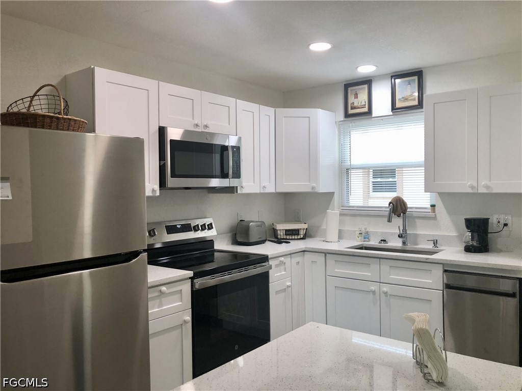16881 Davis Road, Unit 214 Fort Myers, FL 33908 - Photo 8 of 46 a kitchen with a sink a refrigerator a microwave and cabinets