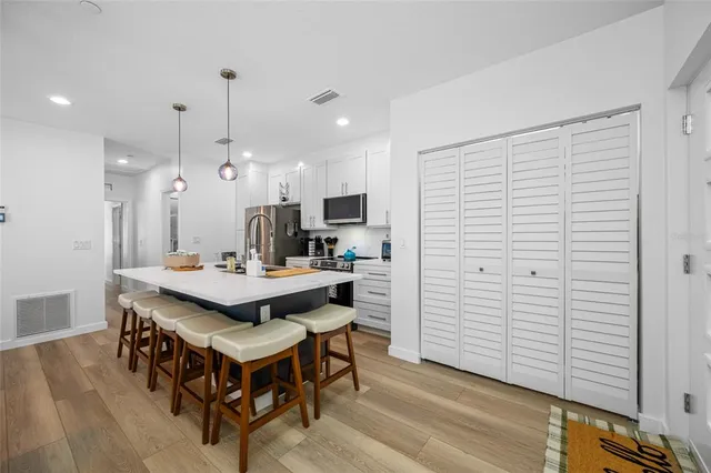 a kitchen with stainless steel appliances wooden floor dining table and chairs