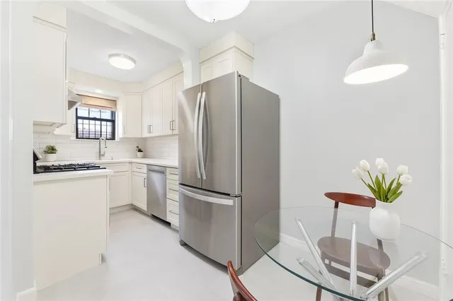 a kitchen with stainless steel appliances a refrigerator a sink a stove a dining table and chairs