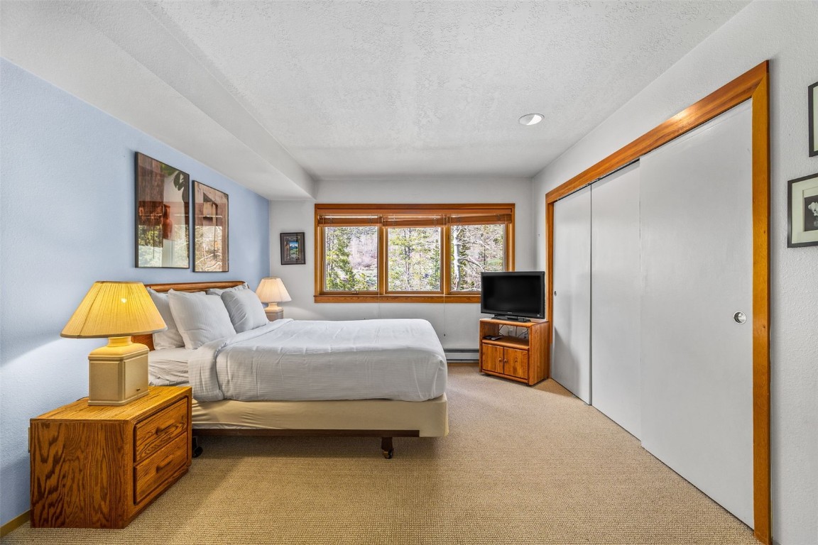 240 Tennis Club Road, Unit 1677 Keystone, CO 80435 - Photo 28 of 46 Bedroom with light colored carpet, a closet, a baseboard radiator, and a textured ceiling