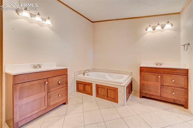 2259 Pathfinder Road Florissant, CO 80816 - Photo 24 of 33 Bathroom with a bath, tile patterned flooring, a textured ceiling, and vanity