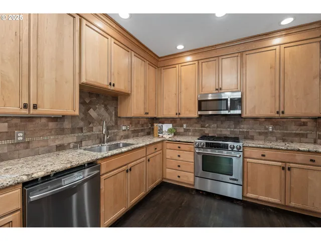 a kitchen with stainless steel appliances granite countertop a sink a stove and cabinets