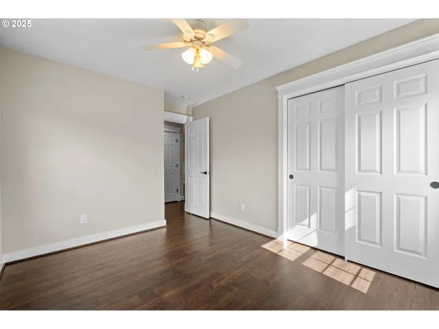 an empty room with wooden floor and a ceiling fan