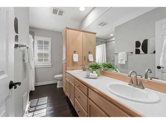 a bathroom with a double vanity sink a mirror a toilet and a shower