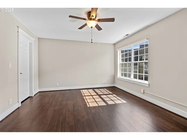 a view of an empty room with a window and wooden floor