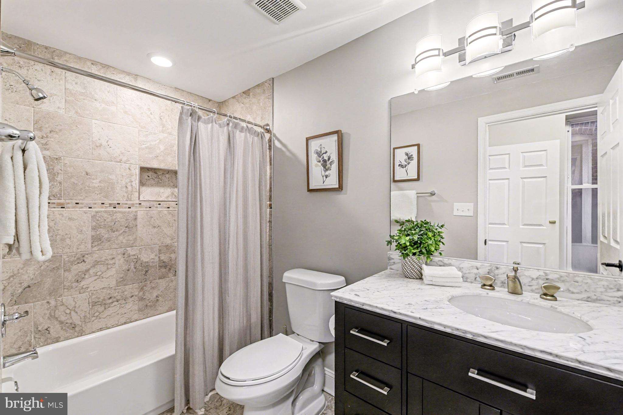 1431 Madison Avenue Baltimore, MD 21217 - Photo 22 of 38 a bathroom with a granite countertop sink toilet a large mirror a shower and a bathtub
