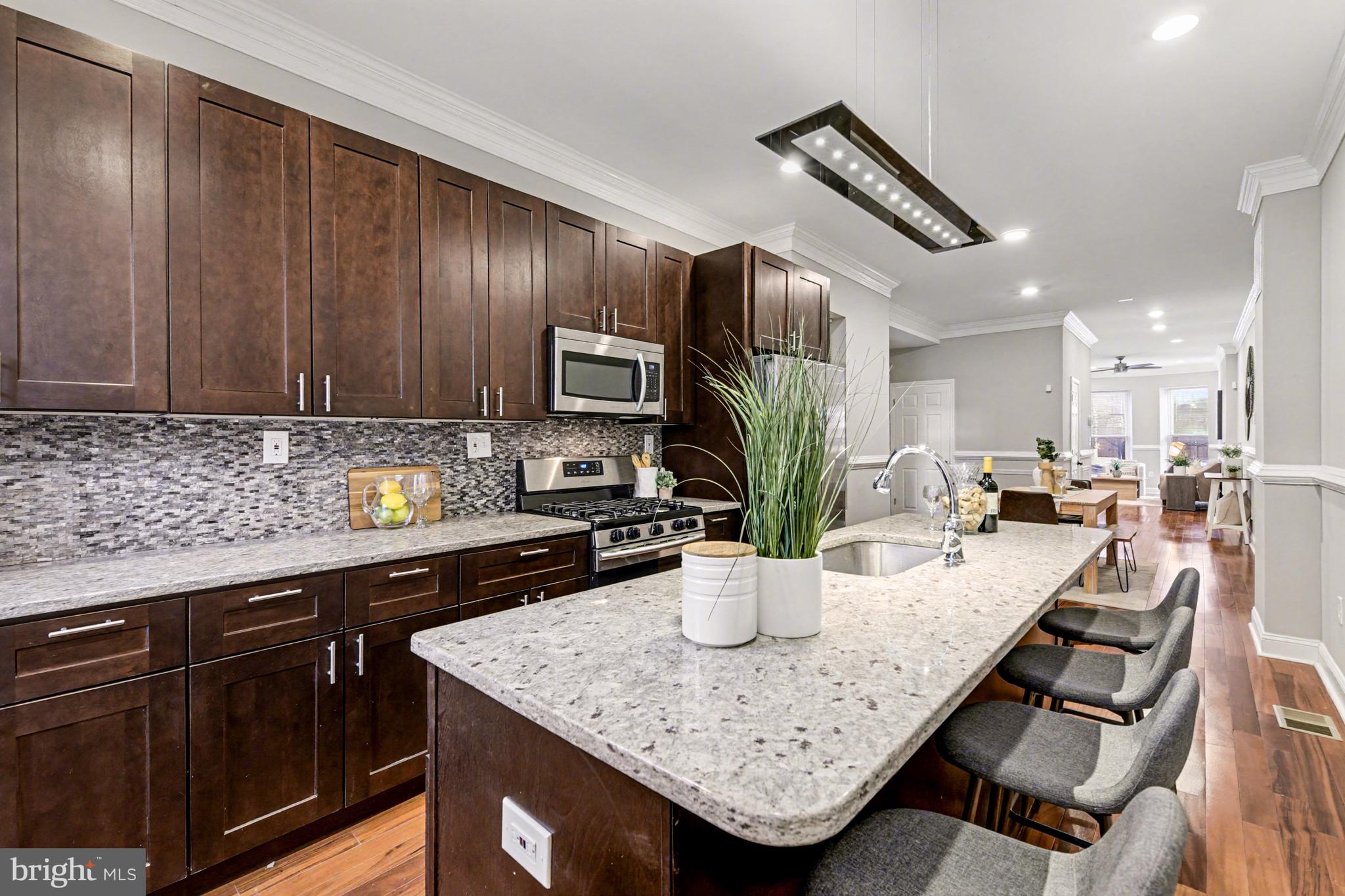 1431 Madison Avenue Baltimore, MD 21217 - Photo 7 of 38 a kitchen with stainless steel appliances granite countertop a sink dishwasher stove and refrigerator with wooden floor