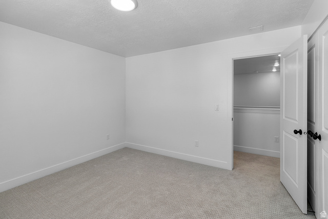 2816 West Aurora Avenue Mapleton, UT 84664 - Photo 16 of 20 Unfurnished bedroom with light colored carpet, a textured ceiling, and a walk in closet