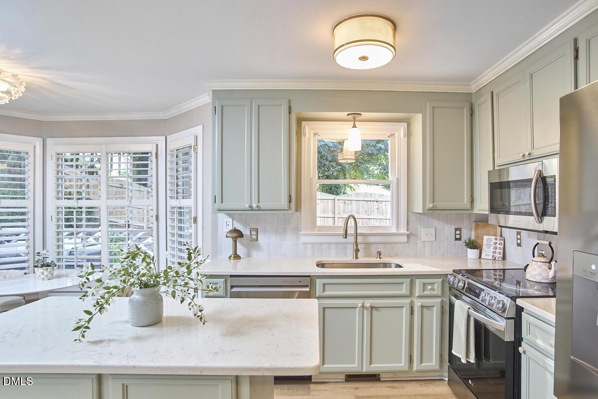 6725 Eastbrook Drive Raleigh, NC 27615 - Photo 14 of 48 a kitchen with a large window cabinets and stainless steel appliances