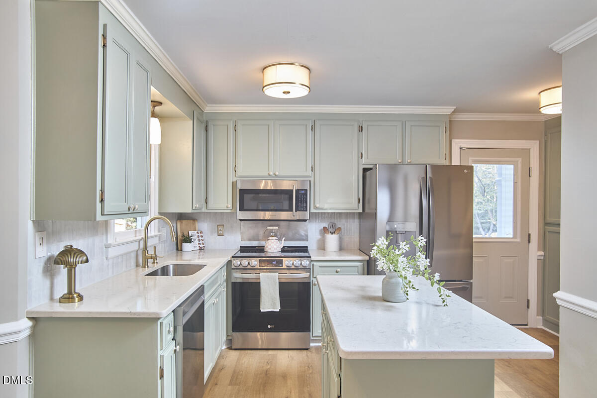 6725 Eastbrook Drive Raleigh, NC 27615 - Photo 15 of 48 a kitchen with stainless steel appliances a sink a stove a refrigerator cabinets and a window