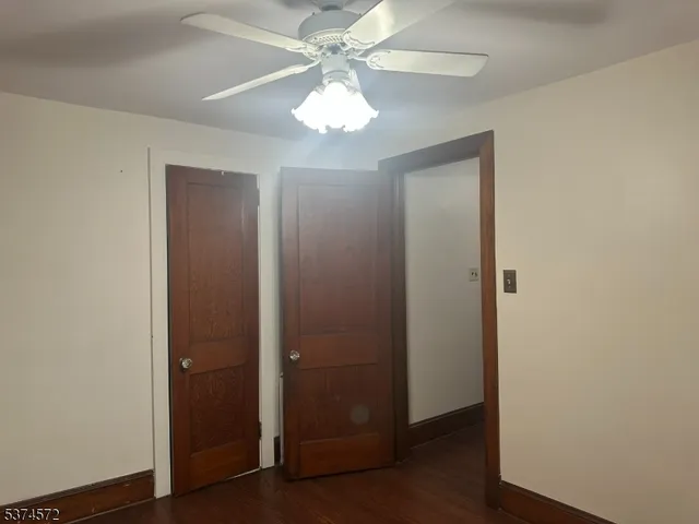 an empty room with wooden floor chandelier fan and closet area
