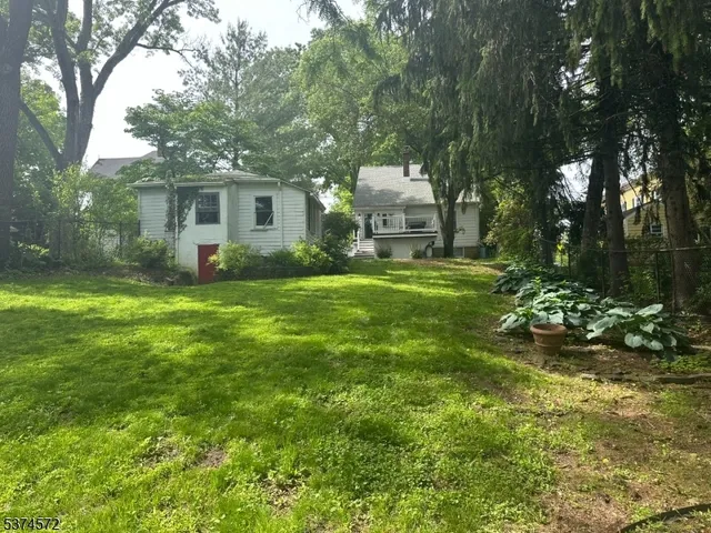 a view of a house with a big yard and large trees
