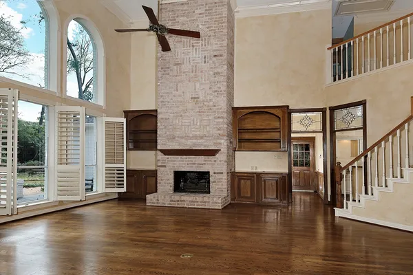 an empty room with wooden floor a fireplace and windows