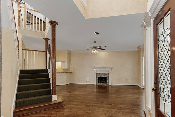 a view of an empty room with wooden floor fireplace and a window