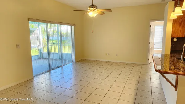 a view of an empty room with window and chandelier fan