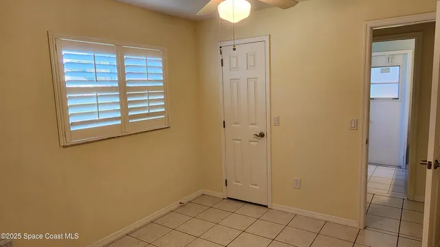 a view of an empty room with window and chandelier fan