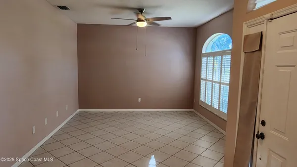 an empty room with chandelier fan and windows
