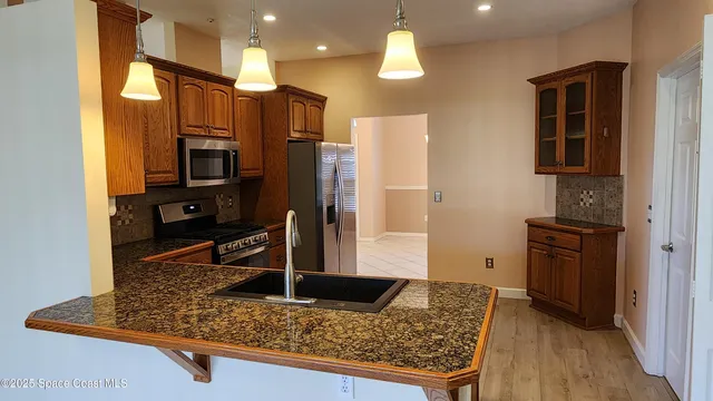 a open kitchen with stainless steel appliances granite countertop a sink and a refrigerator