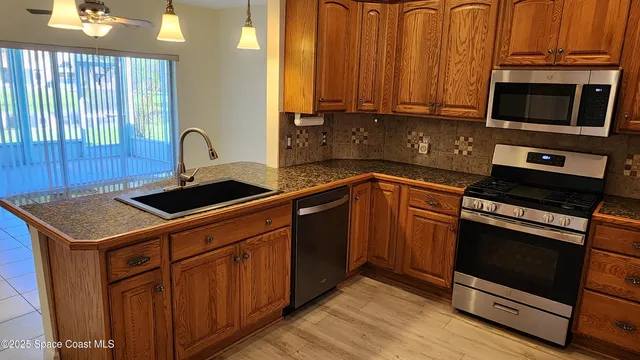 a kitchen with stainless steel appliances granite countertop a stove a sink and a microwave