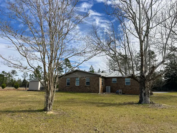 a front view of a house with a yard and large trees