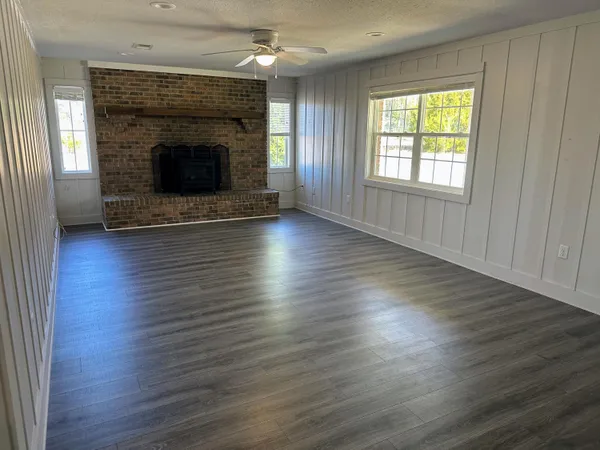 an empty room with wooden floor fireplace and windows