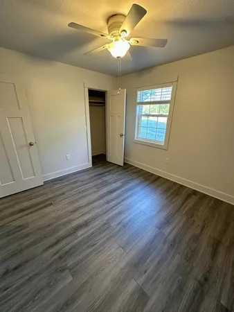 a view of an empty room with window and wooden floor