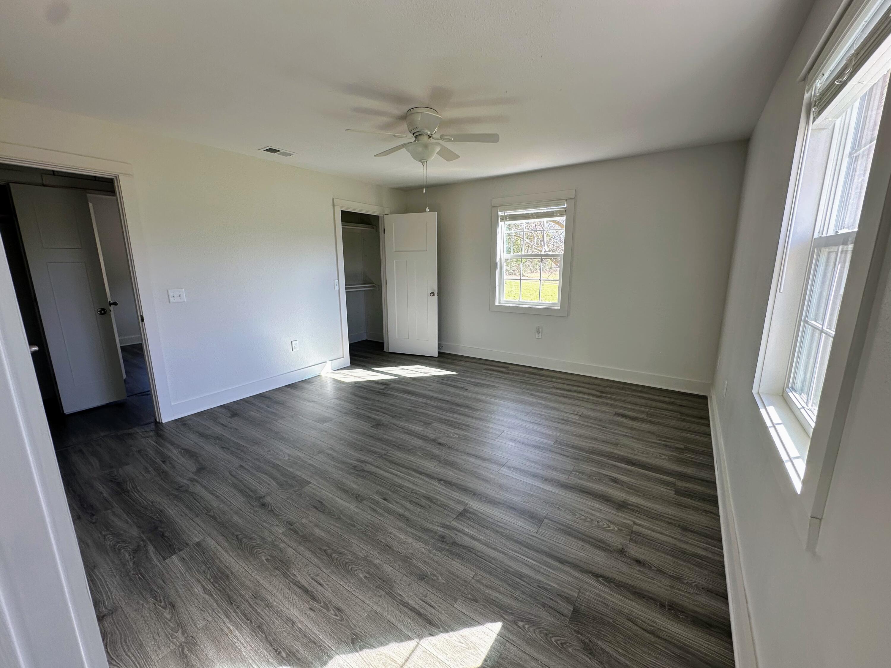 1014 East Indian Creek Ranch Road DeFuniak Springs, FL 32435 - Photo 8 of 17 an empty room with wooden floor and windows