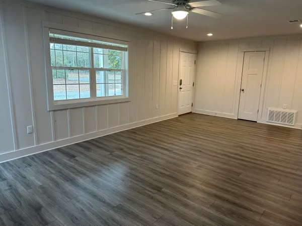 an empty room with wooden floor and windows