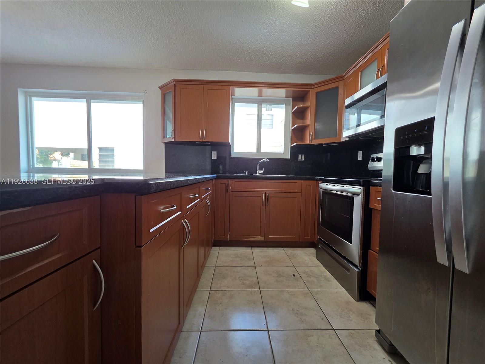 2438 Southwest 114th Avenue Miami, FL 33165 - Photo 4 of 15 a kitchen with stainless steel appliances granite countertop a sink counter space cabinets and a large window