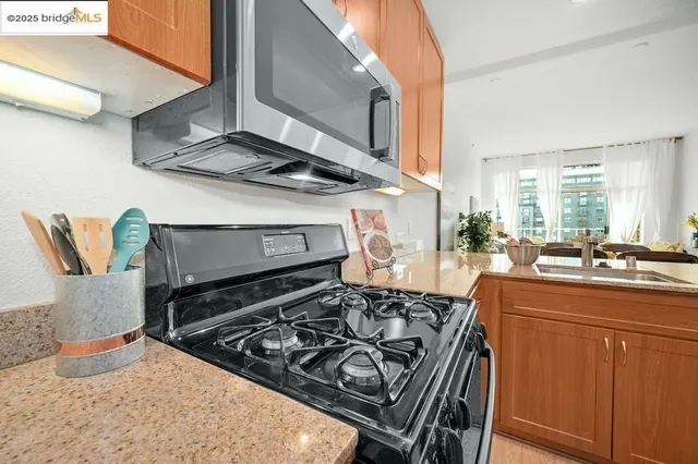 a kitchen with stainless steel appliances a sink a stove a refrigerator cabinets and a chairs