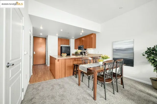 a kitchen with kitchen island a dining table chairs stainless steel appliances and cabinets