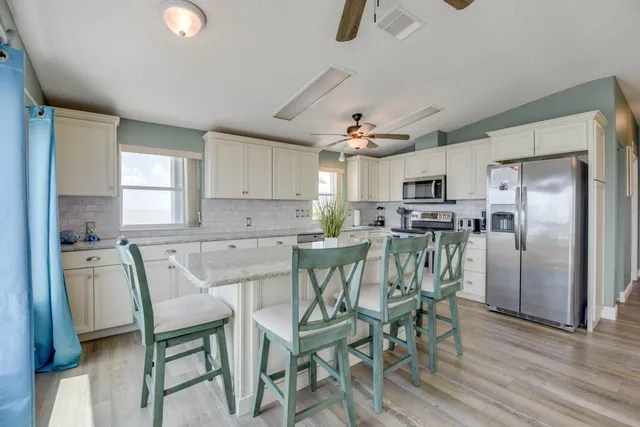 a view of a dining room with furniture a kitchen and chandelier